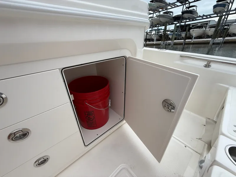 Slide: The Image of Boston Whaler 250 Dauntless 2026 storage compartment with red bucket. - 19