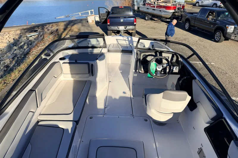 Slide: The Image of 2025 Yamaha Boats AR190 interior with seating and steering wheel, parked near a lake. - 23
