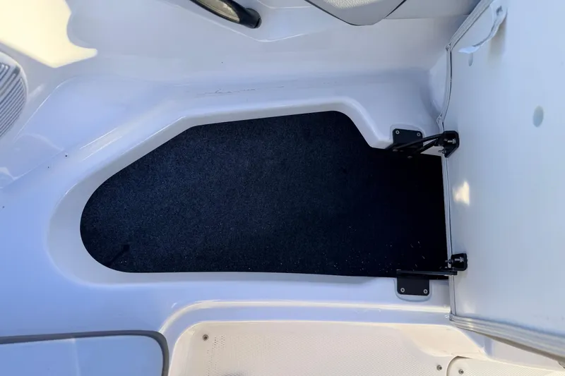 Slide: The Image of 2025 Yamaha Boats AR190 interior storage compartment with black carpet lining. - 39