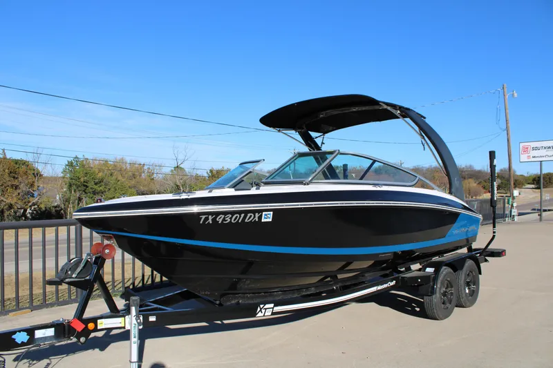 Slide: The Image of 2017 Regal 2100 Bowrider boat on trailer, parked outdoors under clear blue sky. - 3