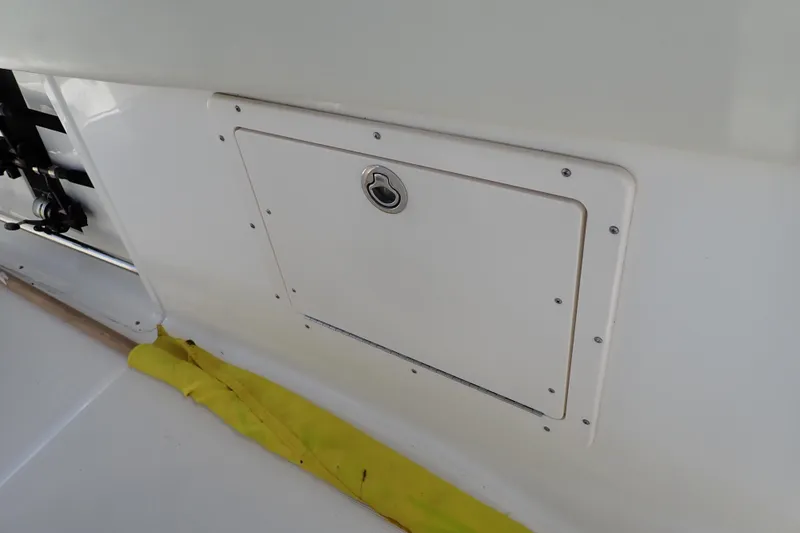 Slide: The Image of 2006 Robalo R220 Center Console storage compartment with latch, featuring a yellow strap. - 37