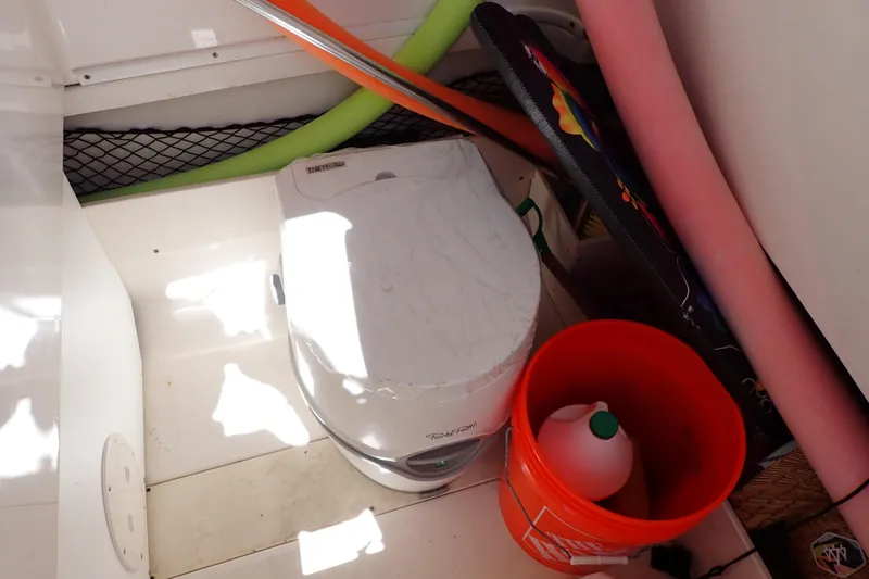 Slide: The Image of 2006 Robalo R220 Center Console boat interior with portable toilet and storage items. - 41