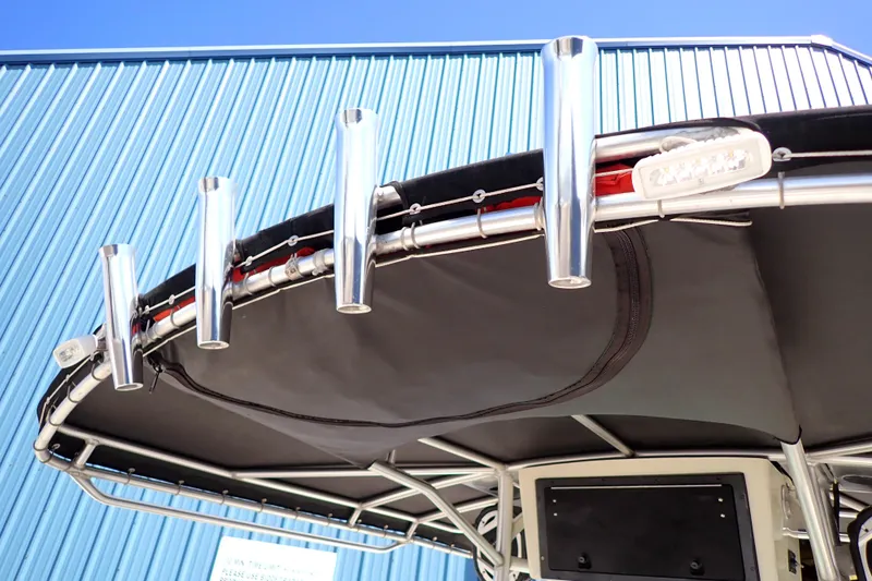 Slide: The Image of 2006 Robalo R220 Center Console boat with rod holders and canopy against blue building. - 52