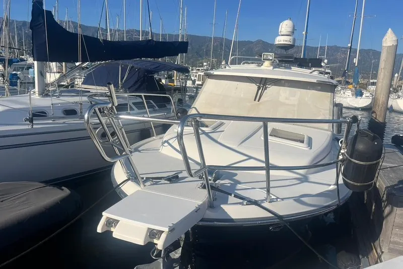 Slide: The Image of 2013 Cutwater C-28 boat docked at marina, featuring blue canopy and spacious deck area. - 2