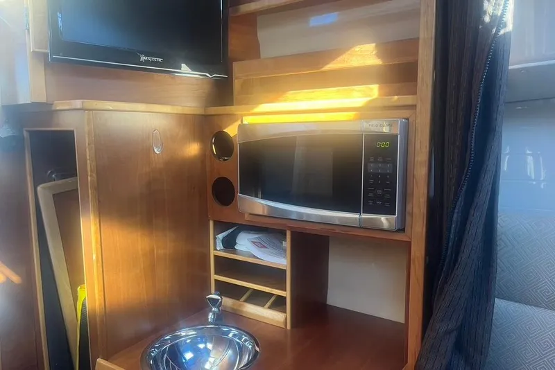 Slide: The Image of 2013 Cutwater C-28 interior with microwave, TV, and sink in wooden cabinetry. - 35
