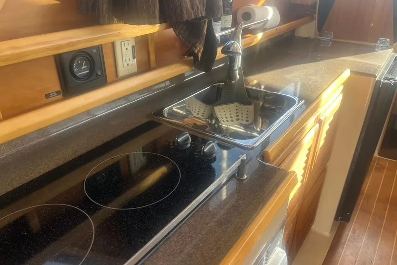 Slide: The Image of 2013 Cutwater C-28 boat kitchen with stove, sink, and wooden cabinetry. - 46