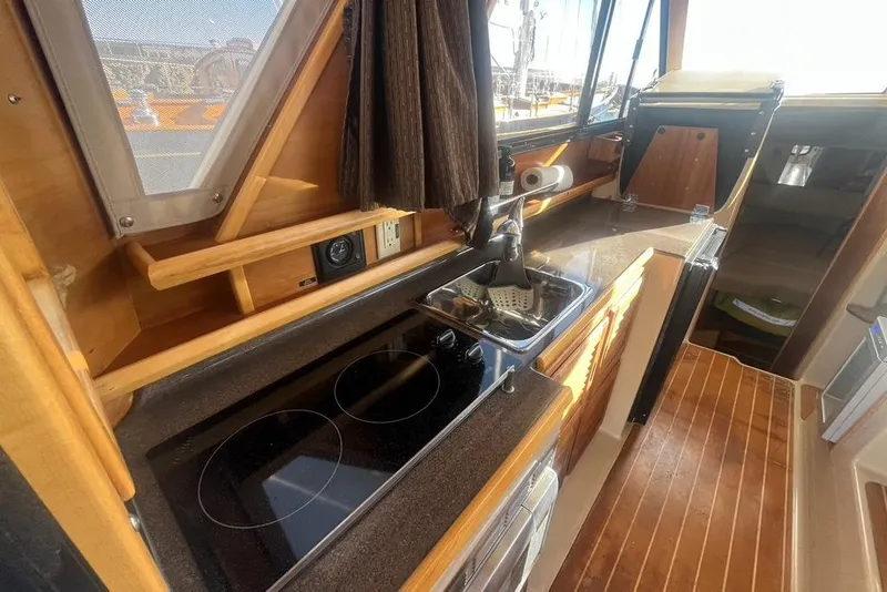 Slide: The Image of 2013 Cutwater C-28 boat interior kitchen with stove, sink, and wooden cabinetry. - 47