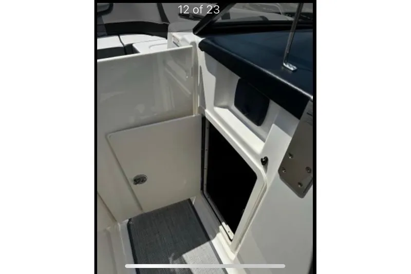 Slide: The Image of 2018 Chaparral 307 SSX boat interior storage compartment with open door. - 12