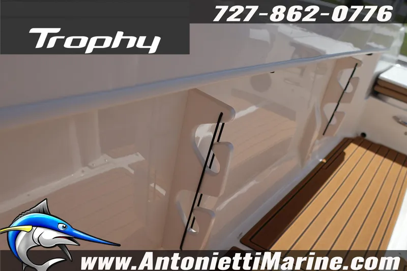 Slide: The Image of 2026 Bayliner Trophy T22CC boat interior with wood finish, contact info, and logo. - 16