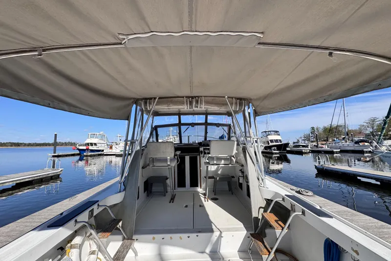 Slide: The Image of 1987 Luhrs Alura 30 boat interior at marina, showcasing helm and seating area. - 10