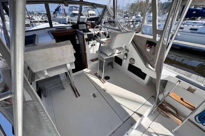 Slide: The Image of 1987 Luhrs Alura 30 boat interior with helm, seating, and marina view. - 16