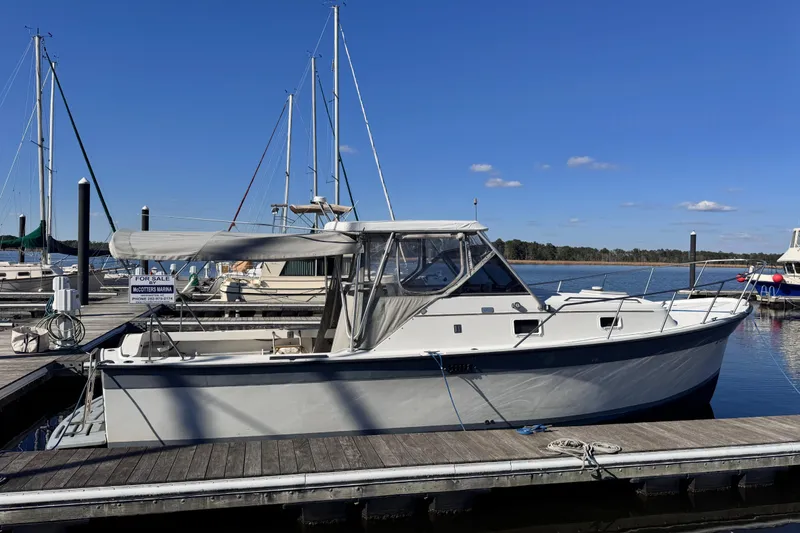 Slide: The Image of 1987 Luhrs Alura 30 boat docked at marina under clear blue sky. - 2
