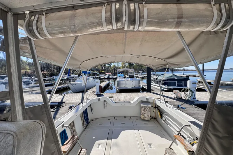 Slide: The Image of 1987 Luhrs Alura 30 boat docked at a marina, featuring a spacious cockpit and canopy. - 22