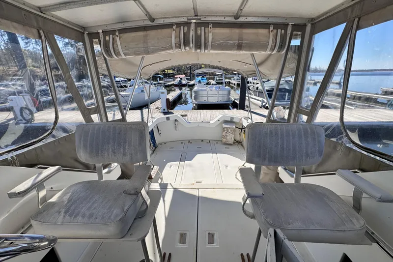 Slide: The Image of 1987 Luhrs Alura 30 boat interior with two seats, docked at a marina. - 23