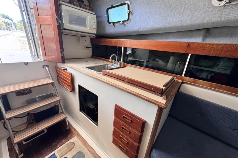 Slide: The Image of 1987 Luhrs Alura 30 boat interior with kitchenette, sink, and wooden cabinetry. - 36