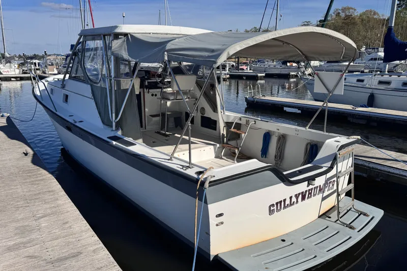 Slide: The Image of 1987 Luhrs Alura 30 boat docked at marina, featuring canopy and open deck. - 4