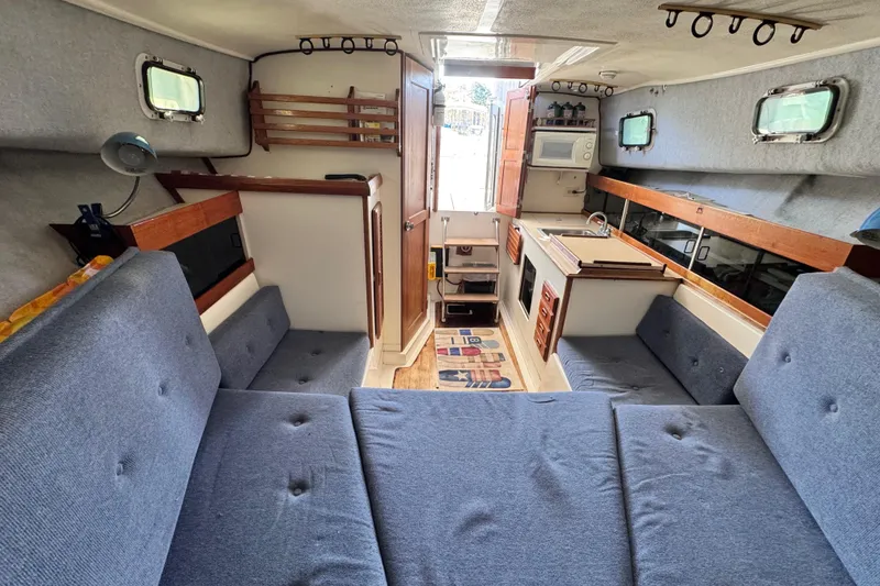 Slide: The Image of Interior of a 1987 Luhrs Alura 30 boat with blue seating and compact kitchen. - 48
