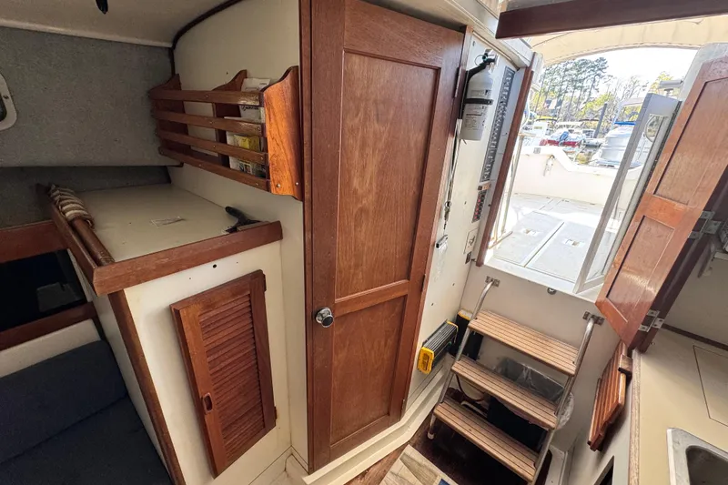 Slide: The Image of 1987 Luhrs Alura 30 cabin interior with wooden cabinetry and steps leading to deck. - 49
