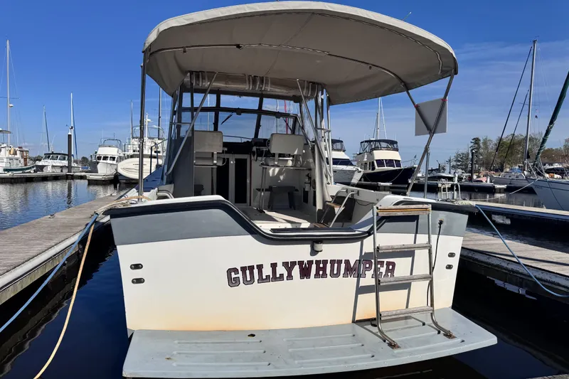 Slide: The Image of 1987 Luhrs Alura 30 boat named "Gullywhumper" docked at a marina under clear blue skies. - 5