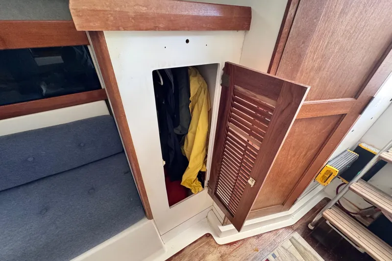 Slide: The Image of 1987 Luhrs Alura 30 interior with open wooden closet and visible clothing. - 50
