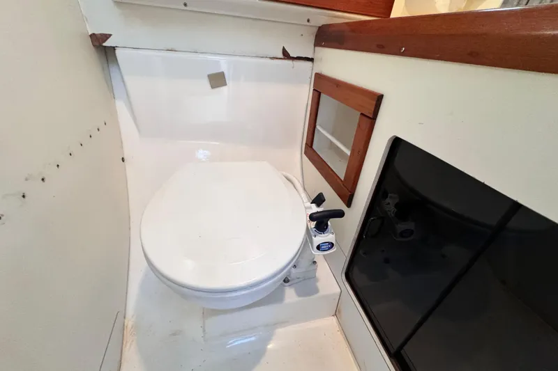 Slide: The Image of 1987 Luhrs Alura 30 boat bathroom with toilet and wooden accents. - 53