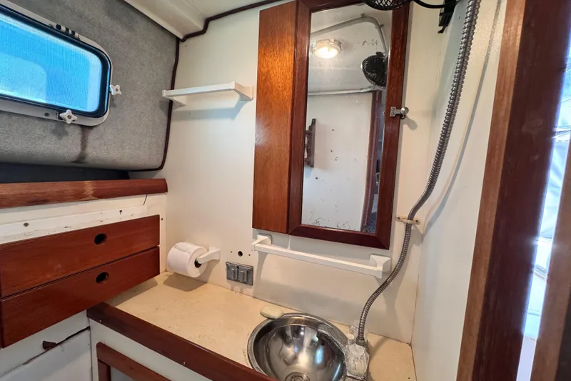Slide: The Image of 1987 Luhrs Alura 30 boat bathroom with sink, mirror, and wooden cabinetry. - 54