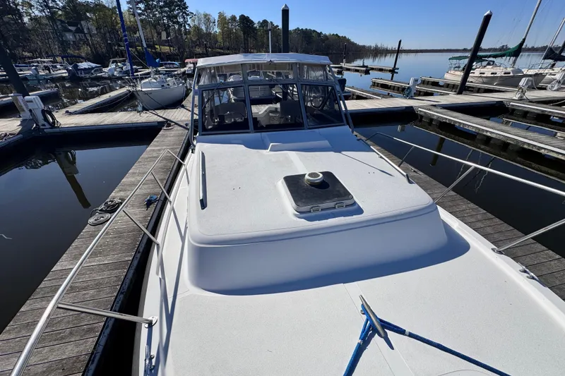 Slide: The Image of 1987 Luhrs Alura 30 boat docked at a marina, surrounded by calm waters. - 7