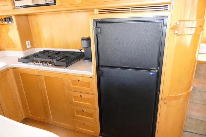 Slide: The Image of 1999 Hampton 490 Pilothouse kitchen with stove, fridge, and wooden cabinetry. - 13