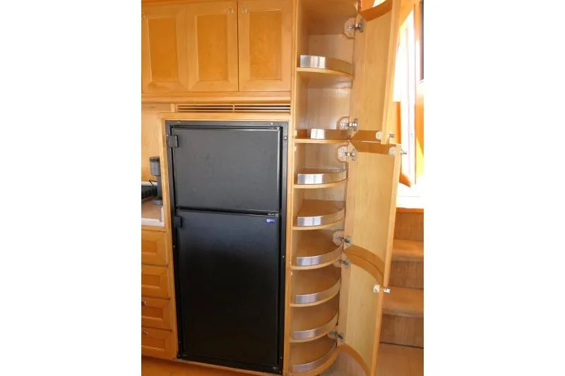 Slide: The Image of Interior of 1999 Hampton 490 Pilothouse with fridge and curved wooden storage shelves. - 14