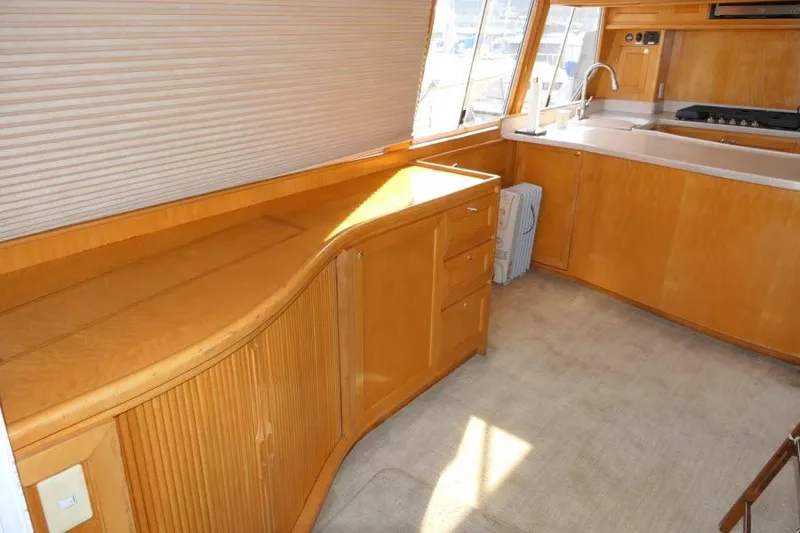 Slide: The Image of Interior of 1999 Hampton 490 Pilothouse yacht with wooden cabinetry and kitchen area. - 2