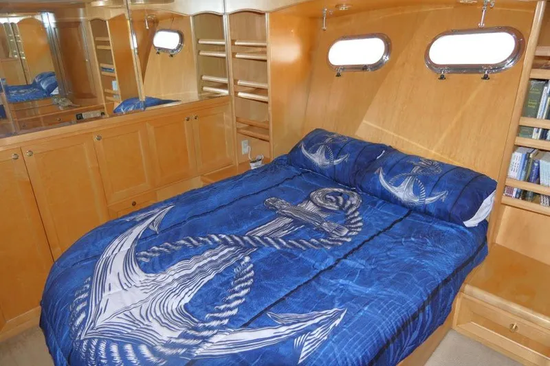 Slide: The Image of Cozy bedroom in 1999 Hampton 490 Pilothouse with nautical-themed bedding and wooden cabinetry. - 26
