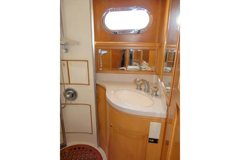 Slide: The Image of Bathroom interior of 1999 Hampton 490 Pilothouse yacht with wooden cabinetry and oval window. - 40