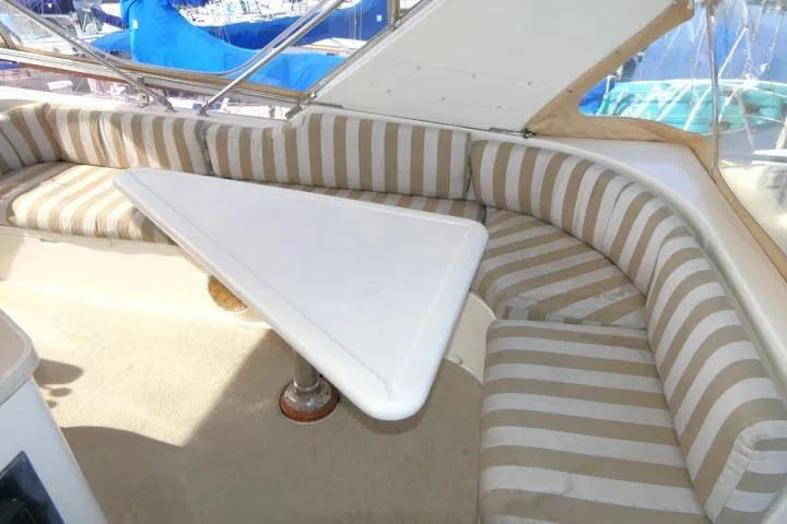 Slide: The Image of Striped seating area with triangular table on 1999 Hampton 490 Pilothouse yacht. - 48