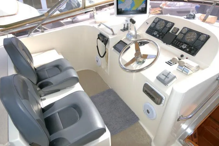 Slide: The Image of 1999 Hampton 490 Pilothouse helm with dual seats, navigation instruments, and steering wheel. - 49