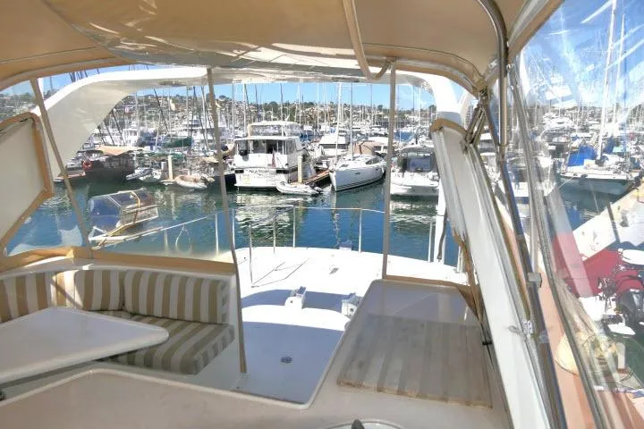 Slide: The Image of 1999 Hampton 490 Pilothouse yacht interior with marina view and striped seating. - 53