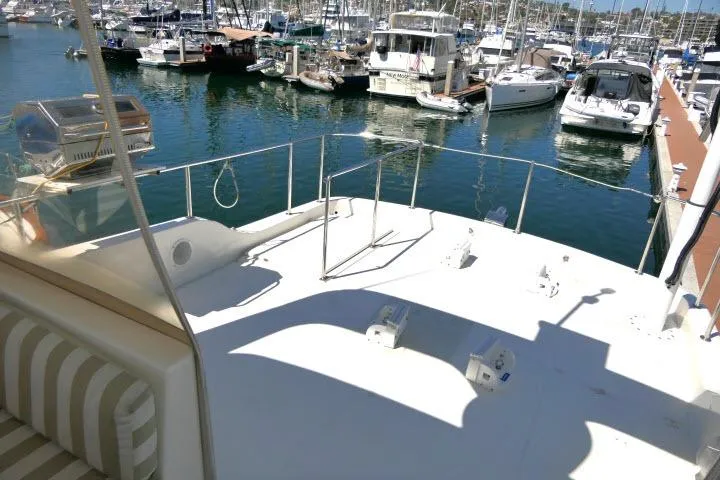Slide: The Image of 1999 Hampton 490 Pilothouse yacht docked at a marina, featuring spacious deck and seating area. - 58