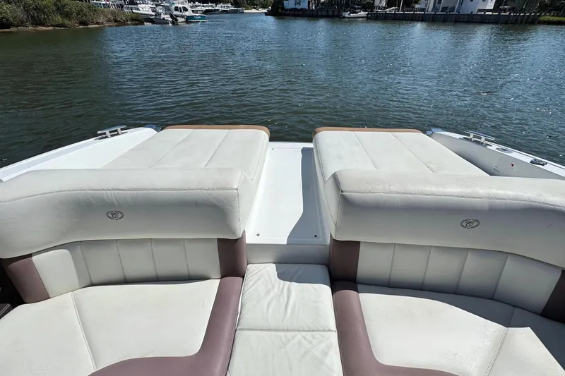 Slide: The Image of 2012 Cobalt 296 boat interior with white leather seating, docked by a calm waterfront. - 14