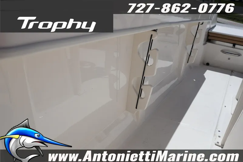 Slide: The Image of 2026 Bayliner Trophy T20CC boat interior with rod holders, contact details, and logo. - 14