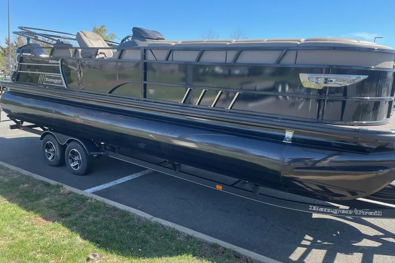 The Image of 2024 Ranger 2500LS pontoon boat on trailer, parked outdoors under clear blue sky. - 0