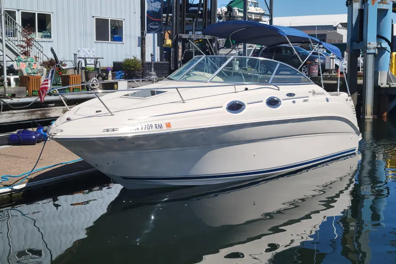 The Image of 2004 Sea Ray 240 Sundancer boat docked at marina, reflecting on water. - 0