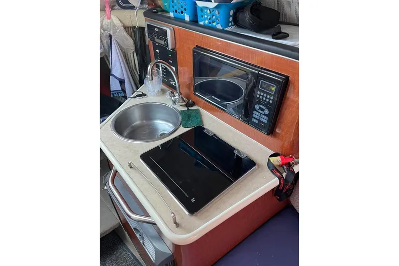 Slide: The Image of Compact kitchen area in a 2004 Sea Ray 240 Sundancer boat with sink and microwave. - 14
