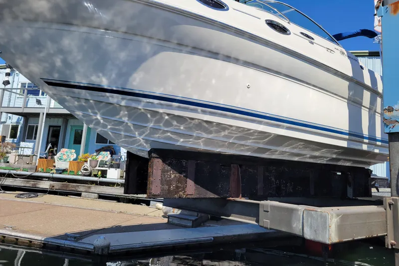 Slide: The Image of 2004 Sea Ray 240 Sundancer boat on lift, reflecting sunlight, dockside view. - 33