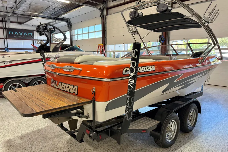 Slide: The Image of 2005 Calabria PRO V boat in showroom, orange and gray design, on a trailer. - 10