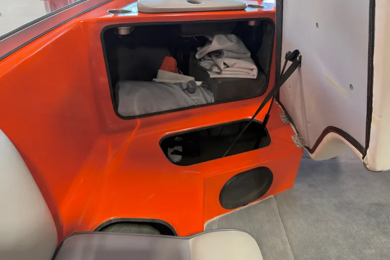 Slide: The Image of Open storage compartment in 2005 Calabria PRO V boat, featuring orange interior and white upholstery. - 29