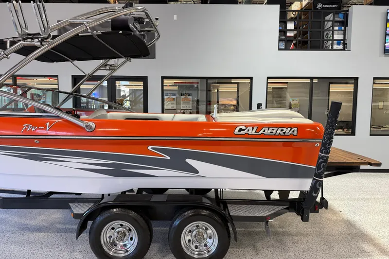 Slide: The Image of 2005 Calabria PRO V boat with vibrant orange and gray design on display indoors. - 4