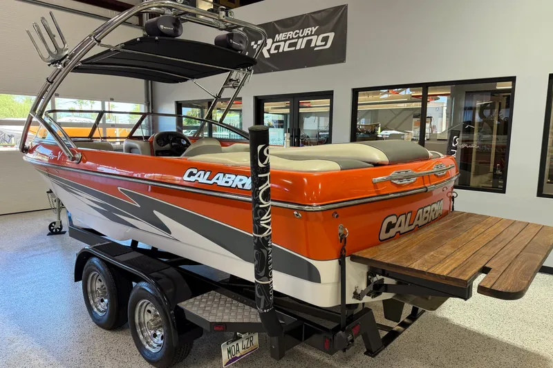 Slide: The Image of 2005 Calabria PRO V boat in showroom, orange and white design, on trailer. - 5