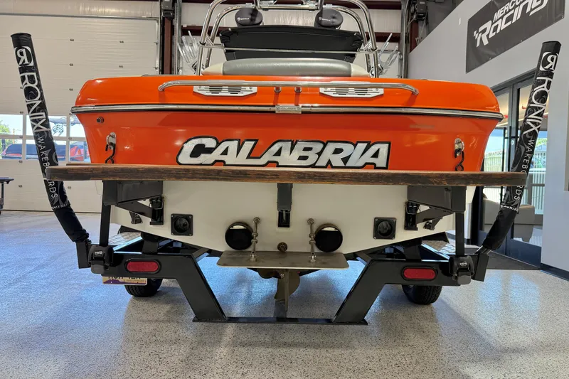 Slide: The Image of 2005 Calabria PRO V boat, orange and white, displayed indoors on a trailer. - 8