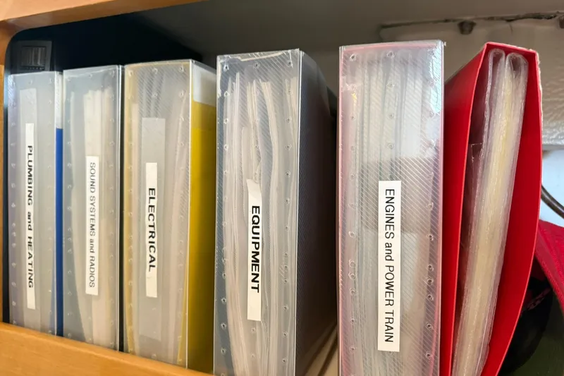 Slide: The Image of Binders labeled for plumbing, sound systems, electrical, equipment, and engines on a shelf. - 113