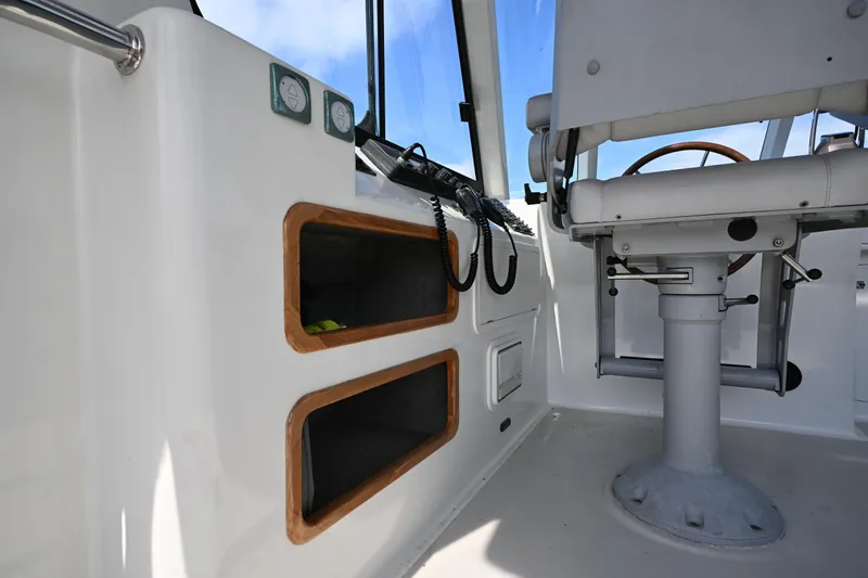 Slide: The Image of Interior of 2002 Roger Hill Power Cat 41.4, featuring helm seat and storage compartments. - 30