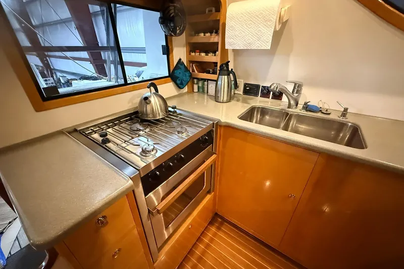 Slide: The Image of Compact kitchen in 2002 Norris Custom Motor Catamaran 41.4 with stove, sink, and wooden cabinetry. - 72